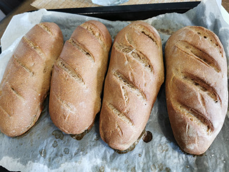 Freshly baked baguettes on a baking sheet in a bakeryの写真素材