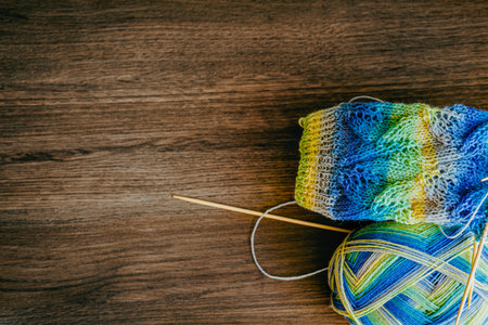 a woolen sock in the process of knitting, threads of varying colors, knitting needles lie on a...