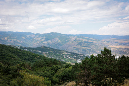 Summer mountain view of Tbilisi, Georgia. Soft clouds cast gentle light over the city and its green...