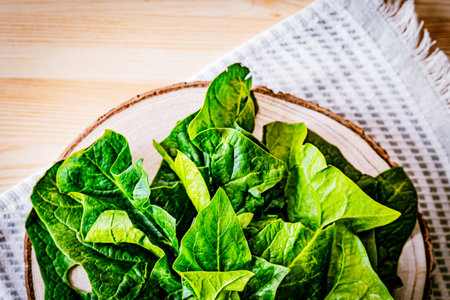 Fresh spinach leaves on a wooden board with a rustic fabric background. A vibrant, organic food concept perfect for healthy eating, vegan diets, and farm-to-table themesの写真素材