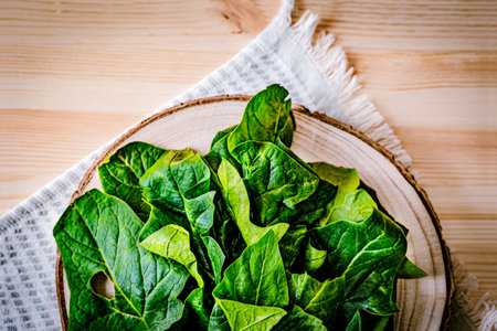 Fresh spinach leaves on a wooden board with a rustic fabric background. A vibrant, organic food...