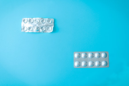 Top view of used and full blister packs with white tablets on blue background. Symbol of medical...