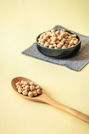 Close-up of wooden spoon filled with dry chickpeas. Minimalist composition with soft natural light and warm tonesの写真素材