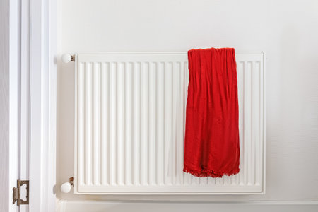 Long red shawl draped over a white radiator in a clean, bright roomの写真素材