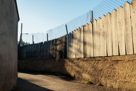 Sunny narrow street with wooden fence and hill landscape in the background, Tbilisi, Georgia. Warm afternoon light creates cozy and peaceful atmosphere.の写真素材