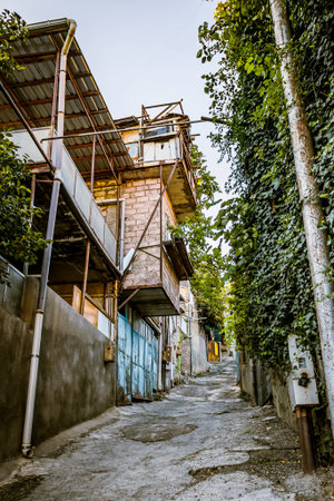 Narrow rustic alley with stone and brick houses under a clear blue sky in Nadzaladzevi district,...