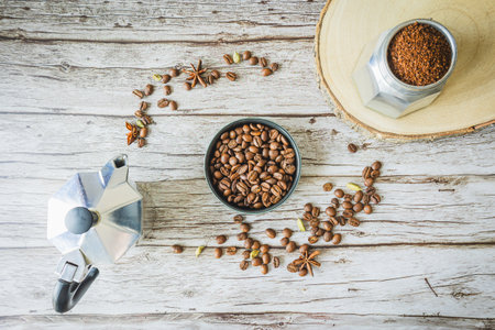 Rustic coffee circle: moka pot, grounds jar on wood slice and bowl of beans encircled by scattered...