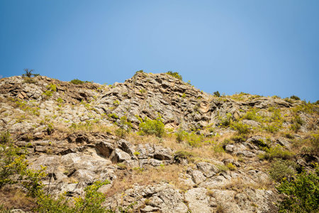 Rocky slope under the blue sky in Mtskheta, Georgia. Harsh summer landscape of the Caucasus region, perfect for travel publications, geology visuals, and outdoor designの写真素材