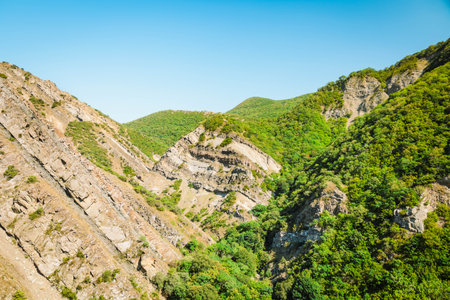 Mountain panorama near Armazi Fortress in Mtskheta, Georgia. Dry grass and forested hills descend into a valley where ancient ruins blend into the wild landscapeの写真素材