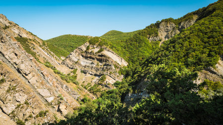 Geological layers of folded rock formations rise among green hills near Armazi Fortress in Mtskheta, Georgia. A dramatic view of natural power and raw Caucasus beautyの写真素材