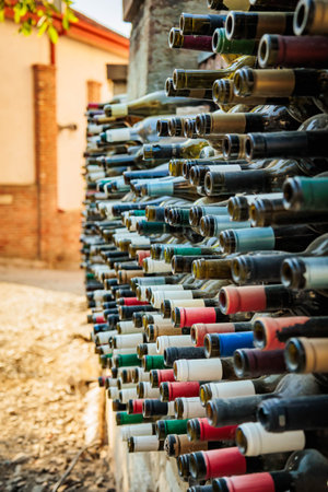 Colorful wine bottle necks embedded in a brick wall, captured in Mtskheta, Georgia. Creative recycled structure representing local winemaking heritage and designの写真素材