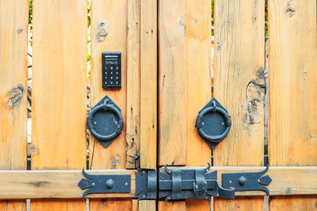 Close-up of rustic wooden gate with black metal handles and a modern access control keypad. Detail of traditional Georgian architecture in Mtskhetaの写真素材