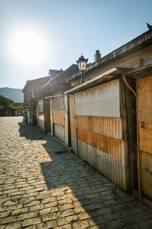Rustic closed market stalls on a cobblestone street with bright morning sunlight, in a traditional village atmosphereの写真素材