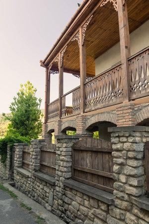Wooden balcony with traditional Georgian carvings surrounded by pomegranate tree branches in old town of Mtskhetaの写真素材