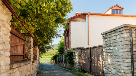 Narrow alleyway leading to the river, framed by stone fences and traditional Georgian architecture in Mtskhetaの写真素材