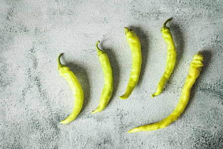 Flat lay of fresh tsitsak peppers on a textured gray background. Minimalist composition, vibrant...