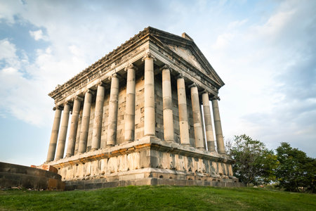Low angle view of the Temple of Garni in Armenia, highlighting its majestic Greco-Roman columns against a cloudy blue skyの写真素材