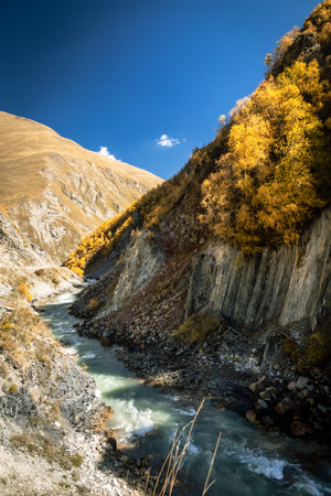 Mountain stream flowing through a quiet canyon near Truso Valley, Georgia. Autumn colors and clear sky create a sense of calm and untouched beautyの写真素材