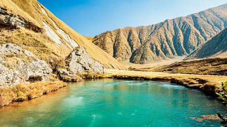 Bubbling turquoise mineral lake in the Caucasus Mountains. Autumn colors, rocky cliffs, and vibrant water make this untouched Georgian landscape unforgettableの写真素材