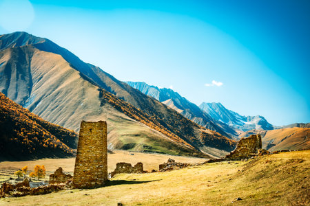 Ancient stone ruins of an abandoned Ossetian village in the scenic Truso Valley, Georgia. Autumn colors, majestic Caucasus mountains, and peaceful historical silenceの写真素材