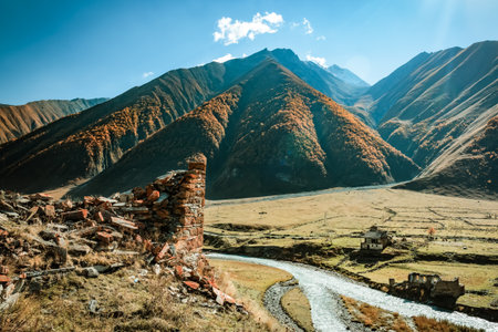 Ruins of ancient Ossetian towers and houses in the Truso Valley, Georgia. Dry golden slopes and clear autumn skies create a timeless and mysterious mountain landscapeの写真素材
