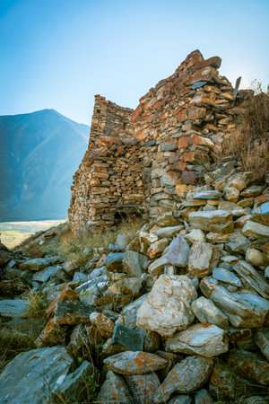 Close-up of weathered stone walls and collapsed masonry from an ancient fortress in Truso Valley, Georgia. Autumn light highlights textures and mountain backdropの写真素材
