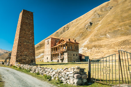 Stone tower and nunnery building in Truso Valley, Georgia. Historic architecture blends with the golden hills under a bright blue skyの写真素材