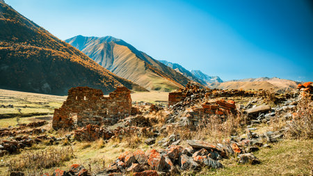 Ruins of ancient Ossetian towers and houses in the Truso Valley, Georgia. Dry golden slopes and clear autumn skies create a timeless and mysterious mountain landscapeの写真素材