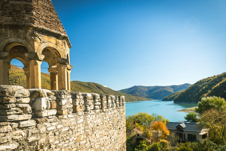 Scenic mountain lake view from ancient stone terrace on a sunny autumn day. Tranquil landscape with colorful trees, distant hills and turquoise water in the highlands of Georgiaの写真素材