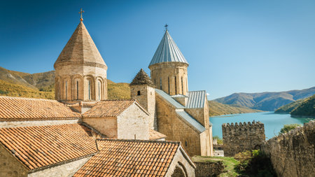 Traditional stone towers and rooftops with panoramic view of a calm lake and surrounding green...