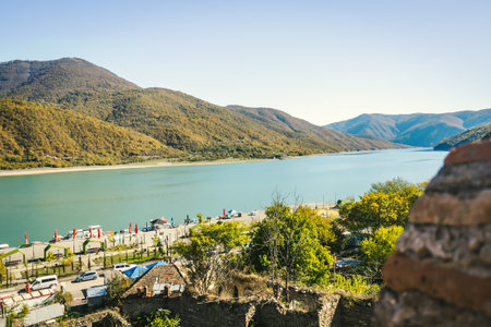 Mountain lake with turquoise water surrounded by forested hills under a clear blue sky. Peaceful nature view on a sunny autumn day in the Caucasus regionの写真素材