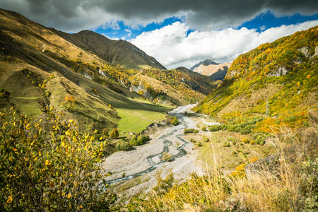Scenic valley view in the Caucasus mountains of Georgia with a winding river and golden autumn...