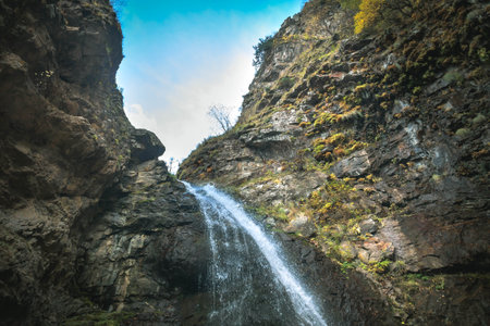 Side view of a narrow waterfall flowing off a cliff edge in Georgia. Dramatic drop, natural rock...