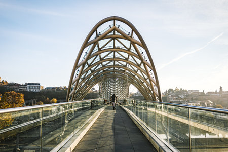 A man rides a bicycle across the Bridge of Peace in Tbilisi, Georgia, on a quiet autumn morning....
