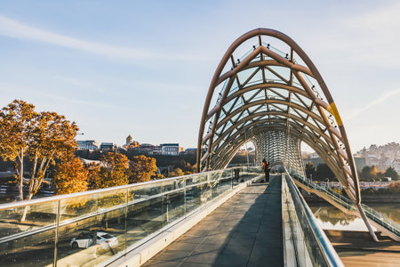 A street cleaner in uniform walks along the Bridge of Peace in Tbilisi, Georgia, on a peaceful...