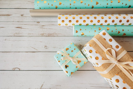 Coordinated gift wrap set with golden hearts and dots on a white wood background. Stylish and cozy...