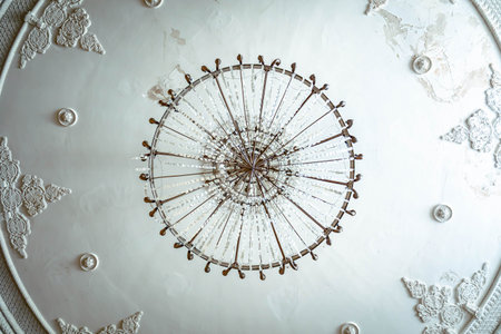 Detailed view of an old crystal chandelier on a decorated ceiling in a former Soviet-era sanatorium in Tskaltubo, Georgia. The mix of decay and elegance evokes nostalgic atmosphere and faded luxuryの写真素材