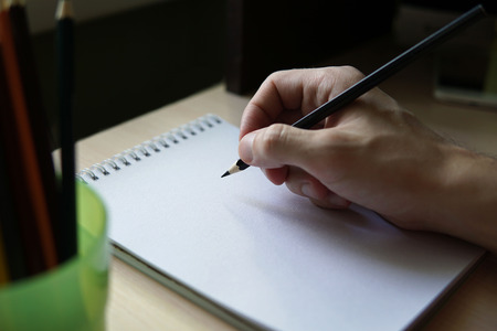 Close up image of man hand sketching on sketchbook at home. Mock up.