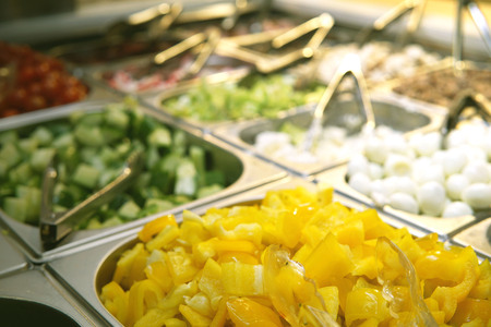 Yellow pepper, cucumbers and other ingredients in a salad bar in a supermarket.の写真素材