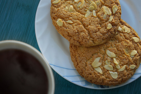 Cup of tea and saucer with two cookies with nuts on the blue table. Top view. Close up.の写真素材