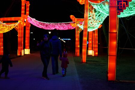 Minsk, Belarus - on March 28, 2019: Chinese lantern festival in Botanical Garden. People walking under Paifang. Chinese architectural arch.のeditorial素材