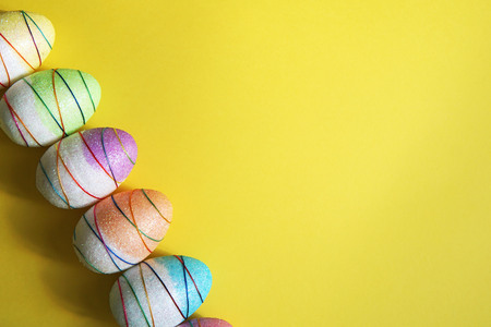 Colorful decorative Easter eggs on yellow background. Copy space.の写真素材