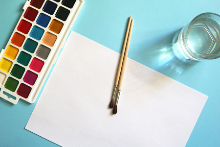 Workplace of an watercolor artist-painter. Blue background, new beautiful paints and brashes.の写真素材