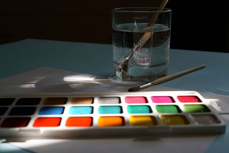 Workplace of an watercolor artist-painter. Blue background, new beautiful paints and brashes. Close up.の写真素材