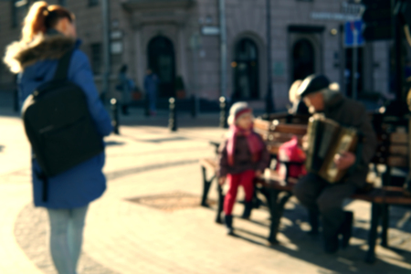 Blurred image of a little singing girl and an old man playing the accordion. Her mother look at them. The concept of the connection of generations.の写真素材
