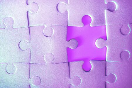 Multiple purple puzzle pieces put together without one piece. View from above. Close up trendy neon monochrome image.の写真素材
