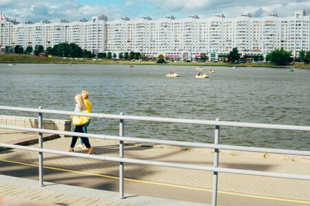 Minsk, Belarus - June 29, 2019. The river Svisloch, view from Nemiga. Two women are walking along the promenade.のeditorial素材