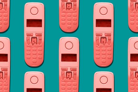 Pattern image of coral color DECT phones turning into a toy phones on blue background. The concept...