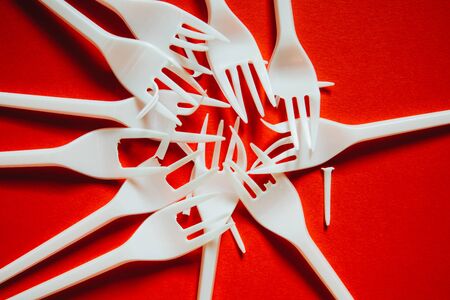 A lot of plastic forks on a red background. The concept of environmental problems, environmental...