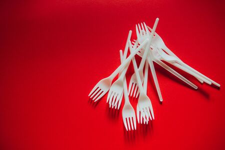 A lot of plastic forks on a red background. The concept of environmental problems, environmental...
